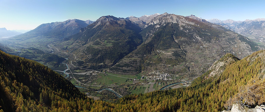 Vue panoramique sur la vallée de la Haute Durance et les montagnes des Hautes-Alpes.
Cette image offre une vue imprenable sur la vallée de la Haute Durance, située dans le département des Hautes-Alpes (05) en région Provence-Alpes-Côte d’Azur. On y aperçoit des paysages alpins majestueux, avec des forêts de mélèzes en premier plan et des montagnes escarpées en arrière-plan. Le fleuve Durance serpente à travers la vallée, irriguant des villages et terres agricoles, dont certains sont directement concernés par des projets d’aménagement controversés, comme les lignes à Très Haute Tension (THT). Cette région est prisée pour ses activités de plein air, notamment la randonnée, le ski et le parapente, offrant des panoramas exceptionnels entre Embrun, Briançon et Guillestre.