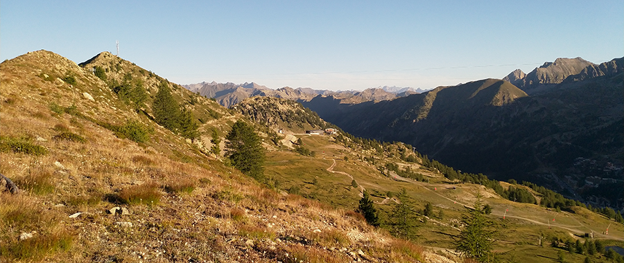 Cette image capture un paysage spectaculaire du Parc national du Mercantour, dans les Alpes-Maritimes, offrant une vue sur une crête montagneuse entre le vallon de Mollières et Isola 2000. On y aperçoit des sentiers serpentant à travers des prairies alpines, avec en arrière-plan la chaîne des Alpes. Ce site naturel, marqué par l’histoire militaire avec d’anciennes fortifications du Mur Alpin, témoigne du passé stratégique de la région. Un lieu idéal pour la randonnée, l’observation de la faune et la découverte du patrimoine alpin.